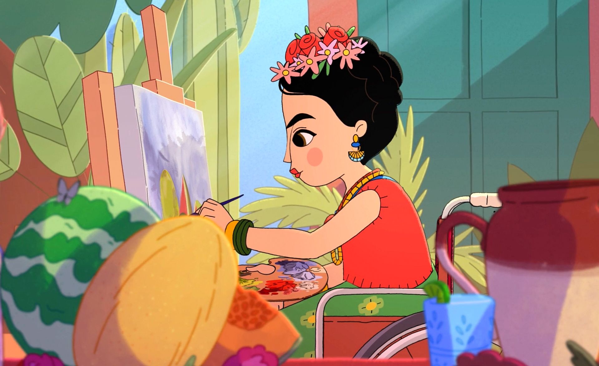 Die erwachsene Frida sitzt in einem Rollstuhl vor einer Staffelei und malt ein Bild